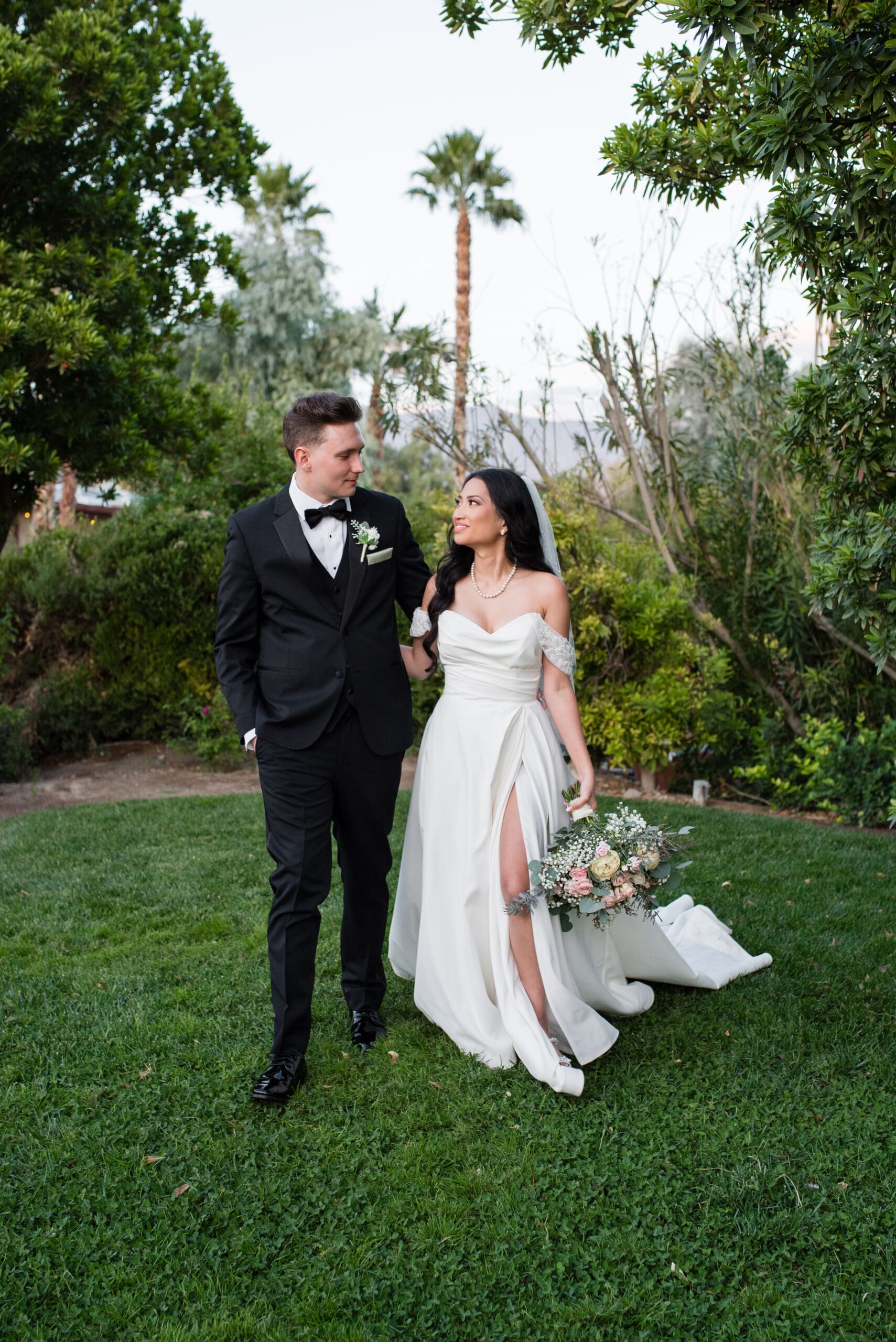 Newlyweds share a joyful moment at sunset in the lush gardens of The Grove in Las Vegas.